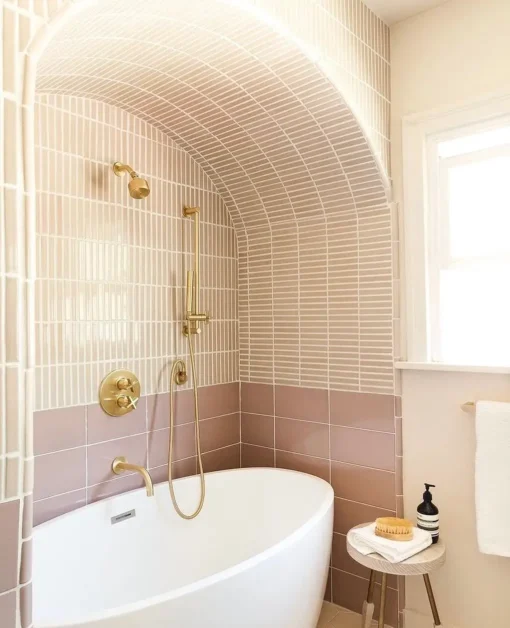 Small pink bathroom with short freestandin tub and gold hardware